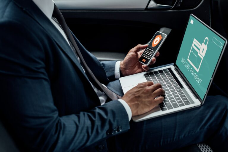 cropped view of african american businessman using laptop and smartphone in car with cyber security